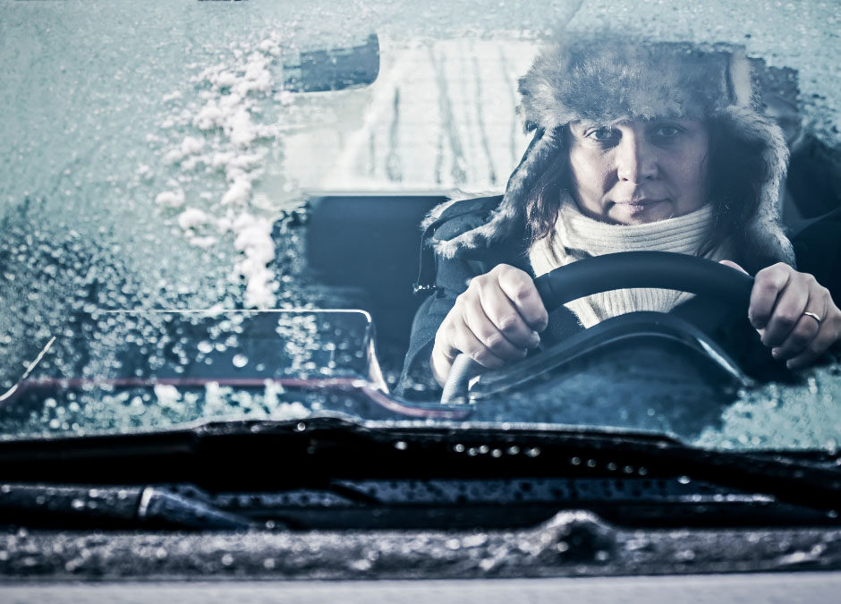 A man driving a car through a snowy landscape, focused on the road ahead.