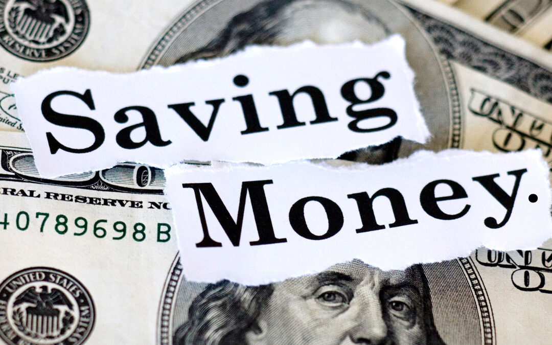 Torn paper with the words "Saving Money" placed on top of multiple US dollar bills -www.dennisnelsoninsurance.com